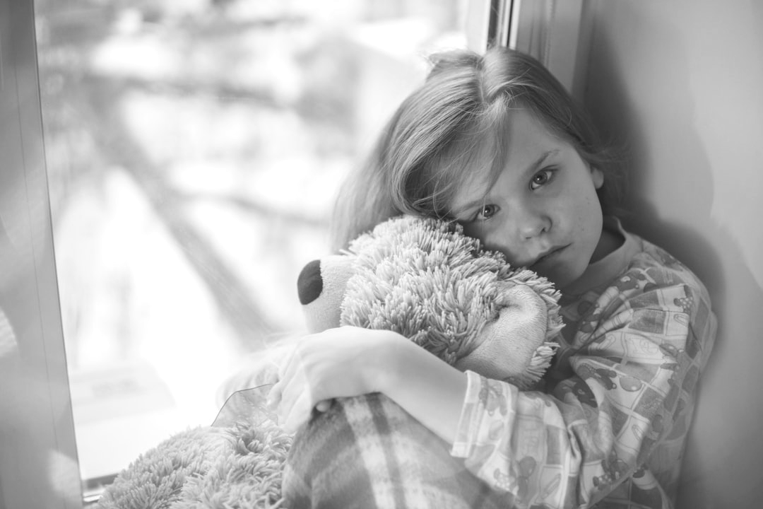 grayscale little girl feeling sad and hugging a teddy bear